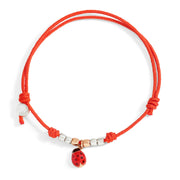 Bracciale Pad Mini Coccinella DoDo con charm coccinella in oro rosa 9K smaltata, mini granelli in argento e oro, cordino rosso regolabile.